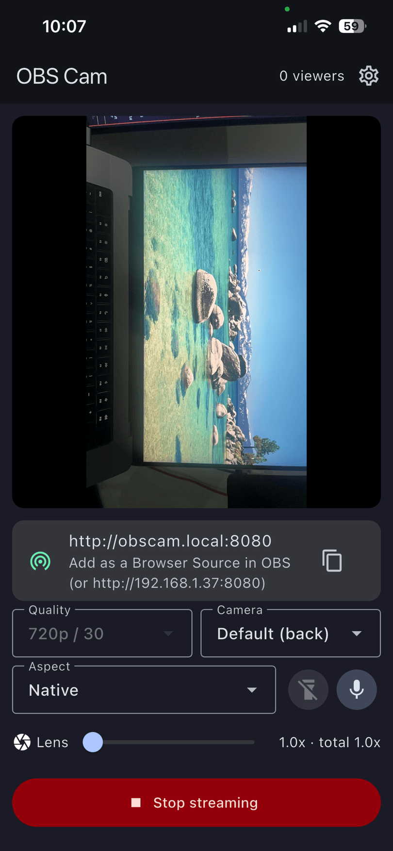 OBS Cam streaming on a phone: a live camera preview of a desk monitor, the address http://obscam.local:8080 to paste into OBS, quality and lens controls, and a red Stop streaming button.